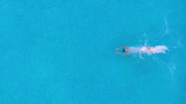 Αργή κίνηση της προβολής από την κορυφή, καθώς ένας άνθρωπος βουτάει στην πισίνα και κολυμπάει κάτω από το νερό — Αρχείο Βίντεο