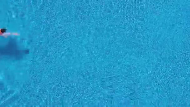 Aerial view of man in red shorts swims in the pool and get out of it — Stock Video