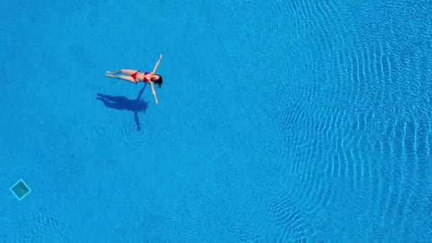 Widok z góry jako kobieta w czerwonym stroju kąpielowym leżąca na plecach w basenie. Koncepcja relaksu — Wideo stockowe