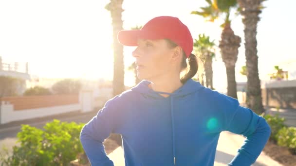 Frau hält beim Joggen an, um die Daten in der Smartwatch-Anwendung zu überprüfen, ruht sich aus und läuft weiter — Stockvideo