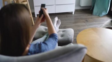 Kadın bir sandalyede oturuyor, yeşil ekran ile Tv izliyor, uzaktan kumanda ile kanal geçiş. Renk anahtarı. Kapalı