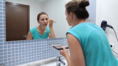 Kadın bir sabah rutin yapar - dişlerini fırçalar, makyaj yapar ve saçlarını koyar.