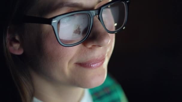 Mujer con gafas mirando en el monitor y navegando por Internet. La pantalla del monitor se refleja en las gafas — Vídeo de stock