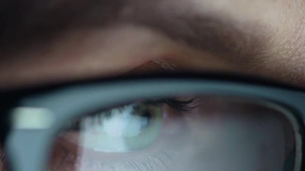 Woman in glasses looking on the monitor and surfing Internet. The monitor screen is reflected in the glasses — Stock Video