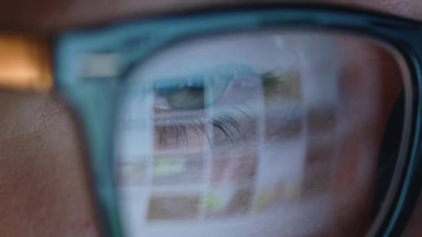 Frau mit Brille schaut auf den Monitor und surft im Internet. der Monitorbildschirm spiegelt sich in der Brille — Stockvideo