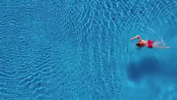 Vista aerea dell'uomo in pantaloncini rossi nuota in piscina — Video Stock