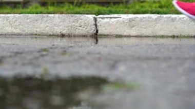 Spor ayakkabılı bir koşucunun bacakları. Spor kadını dışarıda koşuyor, çamurlu su birikintisine giriyor. Yağmurda koşan, su sıçratan tek koşucu. Yavaş çekim