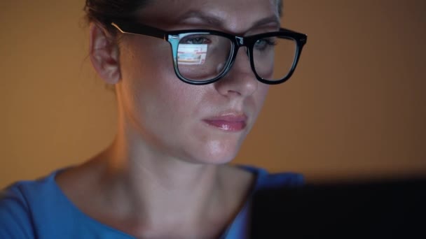 モニター上で探して、インターネットをサーフィンのメガネの女性。モニター画面はメガネに反映されます。 — ストック動画