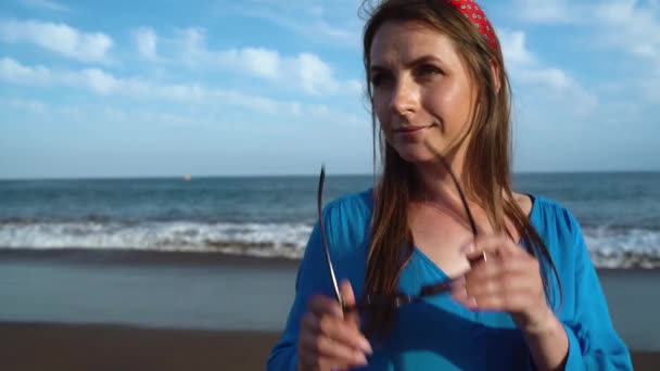 Retrato de una mujer en un hermoso vestido azul en una playa volcánica negra — Vídeos de Stock
