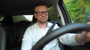 Güneşli havalarda araba kullanan gözlüklü ve beyaz gömlekli sakallı adam