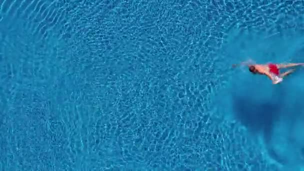 Vista aerea dell'uomo in pantaloncini rossi nuota in piscina — Video Stock