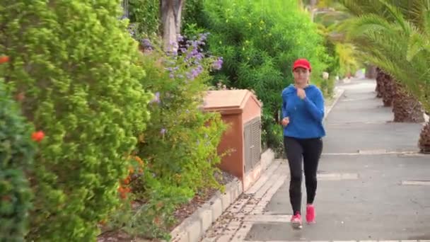 Femme jogging le long de la rue parmi la ruelle tropicale — Video