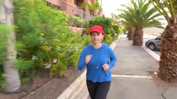 Женщина бегает по улице среди тропической аллеи — стоковое видео