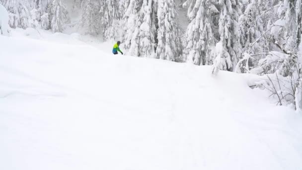 Экстремальный сноубордист едет на свежем порошковом снегу вниз по крутому склону горы. Медленное движение — стоковое видео