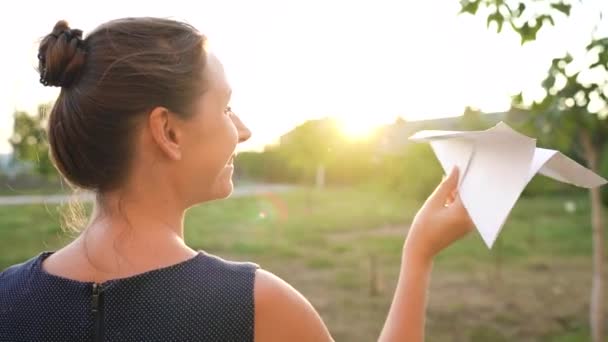 Femeia lansează un avion de hârtie pe fundalul apusului de soare. Conceptul de a visa despre călătorie sau profesia de stewardesă — Videoclip de stoc