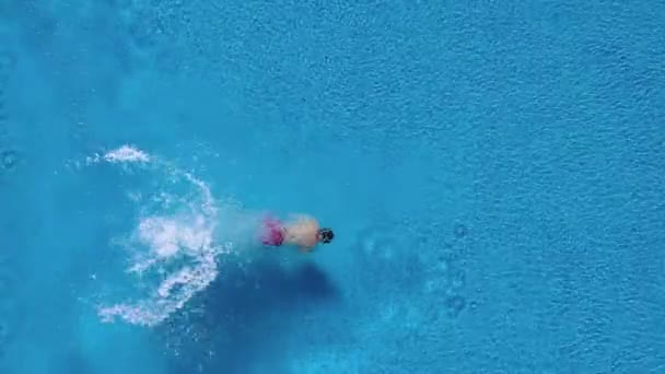 Vista de cima como um homem mergulha na piscina e nada debaixo d 'água — Vídeo de Stock