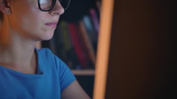 Žena v brýlích, při pohledu na monitor a procházení Internetu. Obrazovka monitoru se odráží v brýle — Stock video
