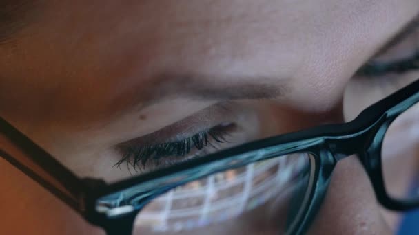 Mujer con gafas mirando en el monitor y navegando por Internet. La pantalla del monitor se refleja en las gafas — Vídeos de Stock