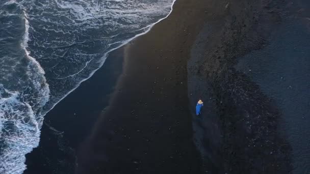 Veduta aerea di una ragazza in abito blu che cammina sulla spiaggia con sabbia nera al tramonto. Tenerife, Isole Canarie, Spagna — Video Stock