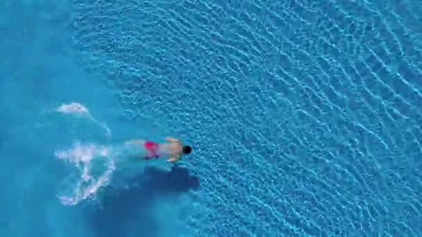 Вид сверху, как человек ныряет в бассейн и плавает под водой — стоковое видео