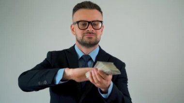 Resmi giyinmiş adam yavaş hareket ederek etrafına dolar saçar ve para yağdırır.