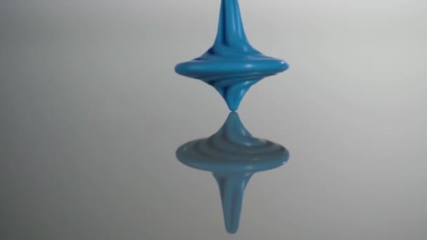 Blue spinning top spinning, wobbling and stop. Вихрь в действии отражается на зеркальной поверхности. Медленное движение — стоковое видео