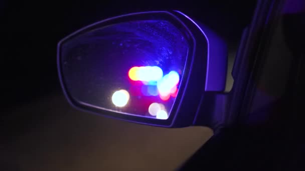 Luces parpadeantes de la policía reflejadas en el espejo retrovisor de un coche por la noche — Vídeos de Stock