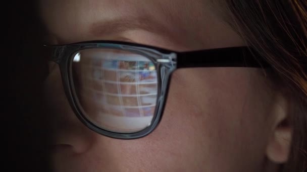 Mujer con gafas mirando en el monitor y navegando por Internet. La pantalla del monitor se refleja en las gafas. Trabaja de noche. Ministerio del Interior. Trabajo remoto — Vídeo de stock