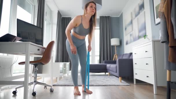 Mujer caucásica entrena los músculos de la espalda en casa durante la cuarentena debido a COVID-19 — Vídeos de Stock