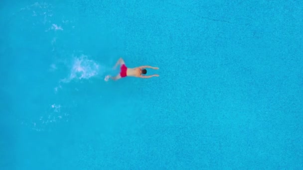 Vista desde la parte superior mientras un hombre se sumerge en la piscina y nada bajo el agua — Vídeo de stock