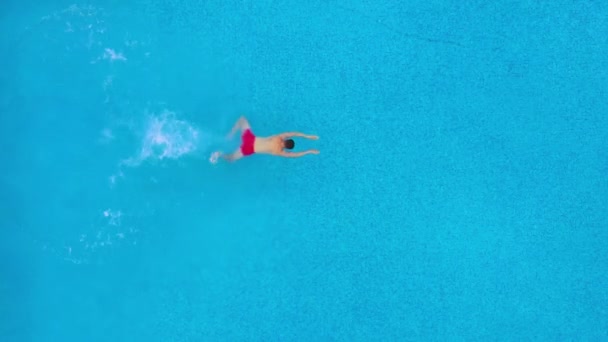 Blick von oben, als ein Mann in den Pool eintaucht und unter Wasser schwimmt — Stockvideo