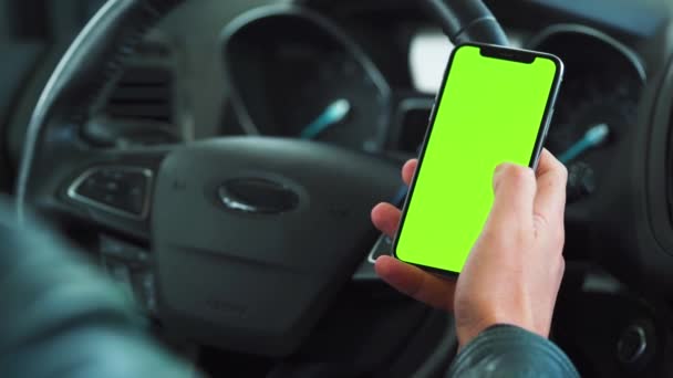 Bestuurder met behulp van een smartphone in de auto. Chromakey smartphone met groen scherm. Auto navigatie. Internetverslaving — Stockvideo