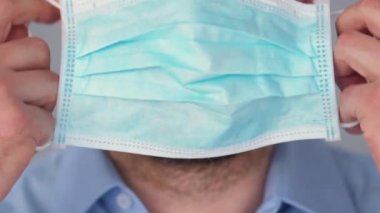 Covid-19 koronavirüsünün pandemik koruması. Tıbbi maske takmış sakallı beyaz bir adamın portresi. Virüs koruması.