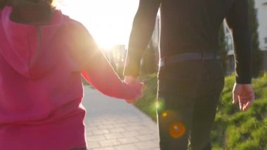 Baba ve kızı gün batımında kendi bölgelerinde dolaşırlar. Çocuk babasının elini tutuyor. Yavaş çekim