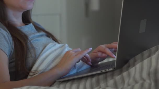 Γυναίκα με γυαλιά που δουλεύει στο λάπτοπ ενώ είναι ξαπλωμένη στο κρεβάτι τη νύχτα. Internet addict ή αϋπνία έννοια. — Αρχείο Βίντεο