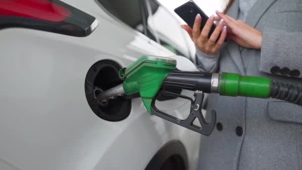 Woman using smartphone while her car is refueling — Stock Video