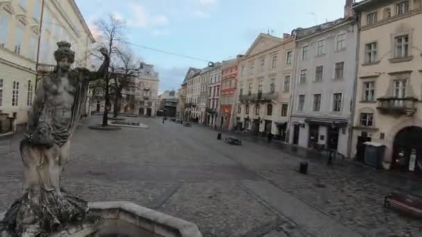 El dron FPV vuela rápido y maniobrable a través de la Plaza del Mercado, alrededor de la estatua de Anfitrite, Lviv, Ucrania. Calles vacías sin gente. Vista aérea del centro histórico de Lviv — Vídeo de stock