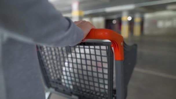 ショッピングカート付きの地下駐車場を通って行く女性のクローズアップ — ストック動画