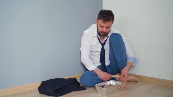 Verontruste man met een baard in slordige formele kleren zit in een leeg appartement. Hij heeft niets te eten. Hij vindt geld in zijn zak en ruikt het.. — Stockvideo