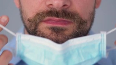 Covid-19 koronavirüsünün pandemik koruması. Tıbbi maske takmış sakallı beyaz bir adamın portresi. Virüs koruması.