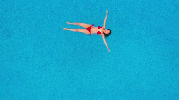 プールに横たわっている赤い水着の女性として上からの眺め。リラックスしたコンセプト — ストック動画