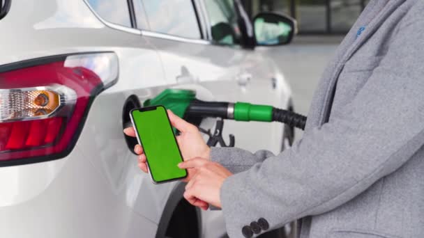 Vrouw gebruikt een mobiele applicatie in een smartphone om te betalen voor het bijtanken van een auto. Smartphone met een groen scherm. Chromatoetsen — Stockvideo