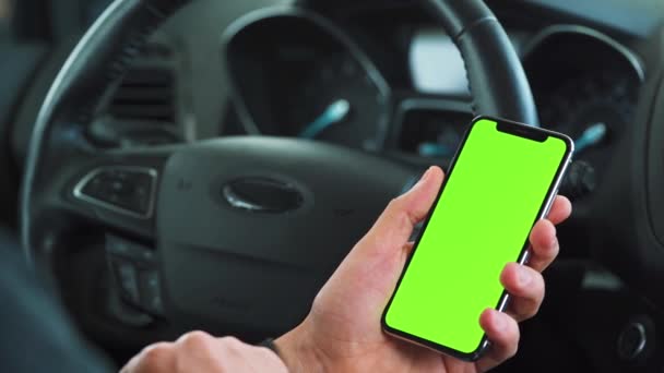 차 안에서 스마트폰을 사용하는 운전자. 녹색 화면을 가진 크로마키 스마트폰입니다. 자동 항법 장치. 인터넷 중독 — 비디오