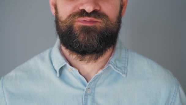 Hombre barbudo con bigote rizado comiendo galletas de chispas de chocolate sobre un fondo de pared gris — Vídeos de Stock