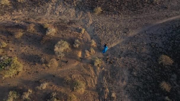 Vista aérea de la mujer en un hermoso vestido azul caminando a través de la reserva natural al atardecer. Prácticas de meditación y respiración. Tenerife, Islas Canarias, España — Vídeos de Stock