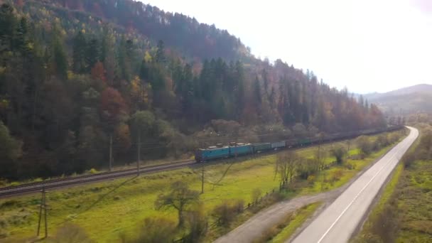 Осень в горах: покрытые лесом горы, движение на дороге и поезд на железной дороге. Видео снималось с разной скоростью - нормальной и быстрой . — стоковое видео