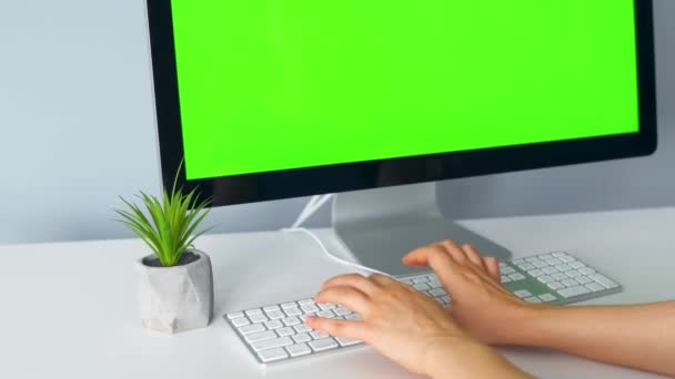 Mujer escribiendo en un teclado de ordenador, monitor con una pantalla verde. Clave de croma. Copiar espacio. — Vídeos de Stock