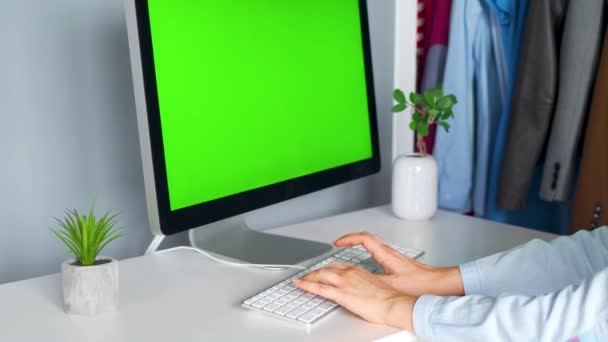 Mujer escribiendo en un teclado de computadora en la oficina en casa, monitor con una pantalla verde. Clave de croma. Copiar espacio . — Vídeos de Stock