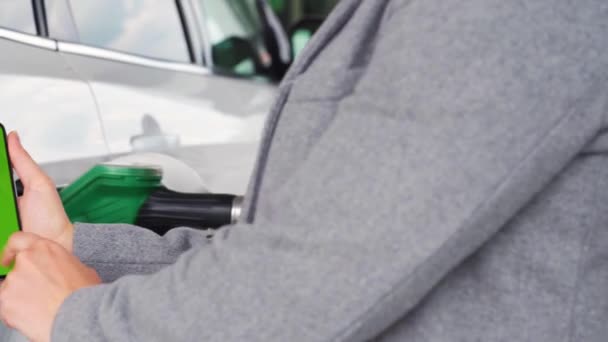 Kobieta używa aplikacji mobilnej w smartfonie, aby zapłacić za tankowanie samochodu. Smartfon z zielonym ekranem. Klucz chromowy — Wideo stockowe