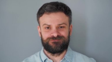 Sakallı, bıyıklı, gri duvarda çikolatalı kurabiye yiyen adam.
